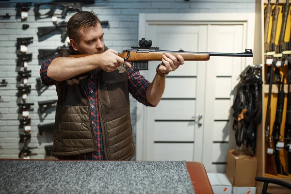 男は銃店で新しいライフルを目指しています ストアで武器を購入男性 狩猟やスポーツシューティング趣味 — ストック写真