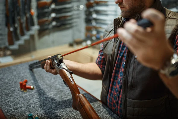 銃屋のカウンターでライフルの銃身を掃除してる 武器店に立つハンターのための機器 狩猟やスポーツシューティング趣味 — ストック写真