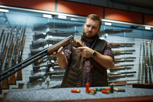 銃屋のカウンターでライフルの銃身を見てる 武器店に立つハンターのための機器 狩猟やスポーツシューティング趣味 — ストック写真