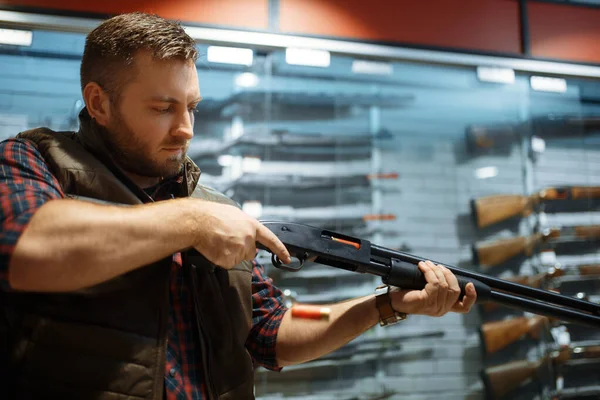 男は銃屋のカウンターで新しいライフルを搭載してる 武器店に立つハンターのための機器 狩猟やスポーツシューティング趣味 — ストック写真