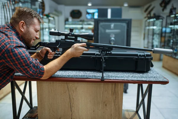 銃屋で狙撃銃を狙う男 武器店に立つハンターのための機器 狩猟やスポーツシューティング趣味 — ストック写真