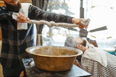 Berber havluyu sıkar, sakal keser. Profesyonel berber dükkanı modaya uygun bir iştir. Erkek kuaför ve müşteri kuaförde, tıraş öncesi prosedürü.