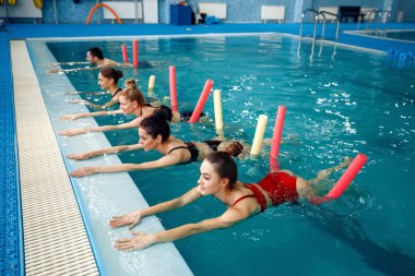 Kadın yüzücüler grubu, havuzda su aerobiği eğitimi. Sudaki kadınlar, spor yüzme egzersizleri.