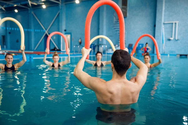 男指导员及女子组 水上运动健美操训练在游泳池中进行 男子和妇女在水中 运动健美运动 — 图库照片