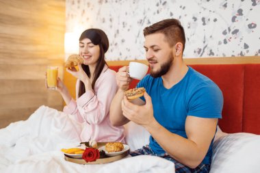 Romantik aşk çifti, evde yatakta kahvaltı, günaydın, şefkatli koca. Genç bir ailede uyumlu bir ilişki. Erkek ve kadın evlerinde birlikte dinleniyor, tasasız bir hafta sonu.