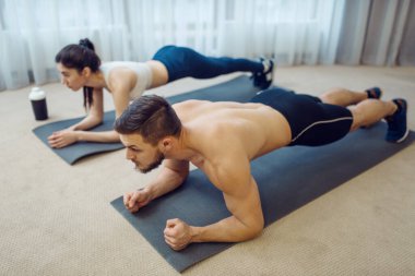 Evde aile çiftleri için sabah sporu. Spor giyim sektöründe aktif erkek ve kadın spor yapıyor. Evlerinde egzersiz yapıyorlar. Sağlıklı yaşam tarzı, fiziksel kültür.