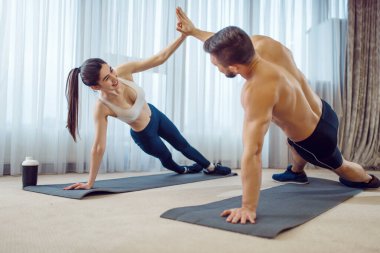Evdeki aşk çifti için sabah sporu. Spor giyim sektöründe aktif erkek ve kadın spor yapıyor. Evlerinde egzersiz yapıyorlar. Sağlıklı yaşam tarzı, fiziksel kültür.