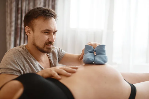 Gelukkig Stel Zwangere Vrouw Man Speelt Met Kleding Voor Pasgeborenen — Stockfoto