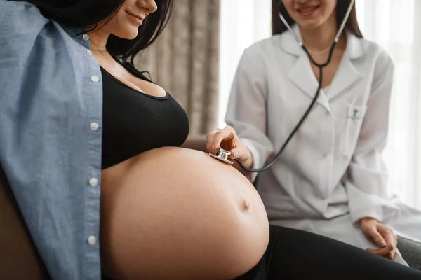 お腹のある妊婦さんと自宅でセラピスト 妊娠中の母親と胎児の健康管理 期待のお母さん健康的なライフスタイル — ストック写真