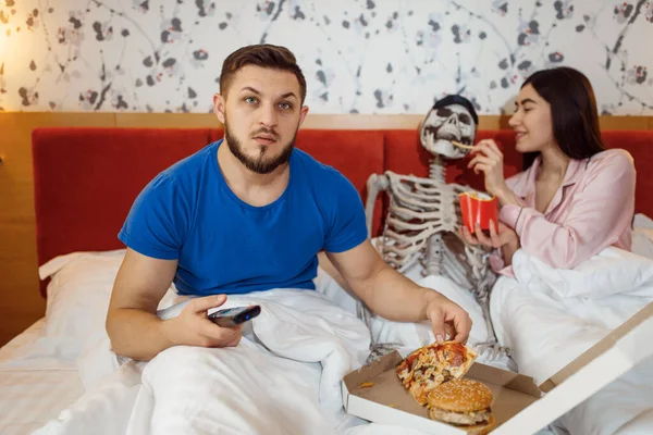 Esposo Viendo Televisión Esposa Alimentando Esqueleto Humano Cama Mala Relación —  Fotos de Stock