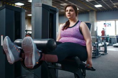 Şişman kadın pres yapıyor, spor salonunda egzersiz yapıyor, aktif antrenman yapıyor. Kadın aşırı kilolarla, obeziteye karşı aerobik egzersizlerle, spor kulüpleriyle mücadele ediyor.