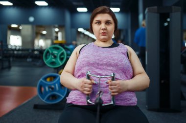 Kilolu bir kadın spor kulübünde egzersiz yapıyor, eğitmenle fitness antrenmanı yapıyor. Kadın aşırı kiloyla, obeziteye karşı aerobik egzersizle, spor salonuyla mücadele ediyor.