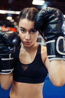 Ringde siyah boks eldivenli bir kadın, yakın görüş, boks eğitimi. Spor salonunda kadın boksör, spor kulübünde kız kickboksör, antrenman yapıyor.