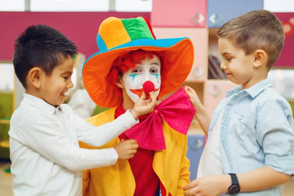 小男孩兴高采烈地摸着红小丑的鼻子 孩子们在一起玩耍 生日派对在游戏室 婴儿假期在操场上 童年的快乐 孩子气的闲暇 — 图库照片