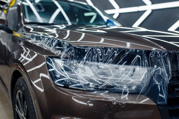 車のフードの透明保護フィルム 自動車の塗料を傷から保護するコーティングのインストール ガレージで新しい車 チューニング手順 — ストック写真