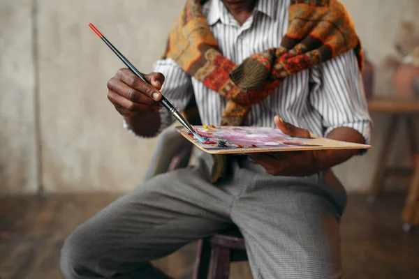 筆とパレットで笑顔の画家は イーゼルに座っている 男性アーティストは彼の職場で絵を描く ワークショップのクリエイター作品 — ストック写真