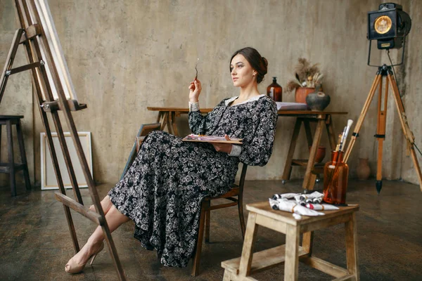 画笔和调色板的女画家坐在艺术工作室的画架前 艺术家在她的工作场所 创意大师在车间 — 图库照片