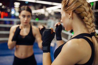 Ringde boks bandajlı kadınlar, boks eğitimi. Spor salonunda kadın boksörler, spor kulübünde kickboks antrenmanı partnerleri, yumruk pratiği.
