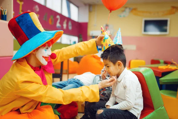 Grappige Clown Zet Een Pet Het Hoofd Van Kleine Jongens — Stockfoto