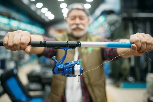 Maschio Pescatore Mostra Asta Con Mulinello Nel Negozio Pesca Attrezzature — Foto Stock