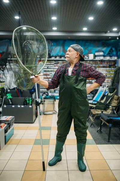 Manlig Sportfiskare Gummioverall Håller Nät Fiskebutik Krokar Och Grannlåt Bakgrunden — Stockfoto