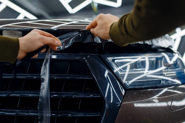 男工在车篷上切割透明的保护膜 安装保护汽车油漆不被刮伤的涂料 车库里的新车 调音程序 — 图库照片
