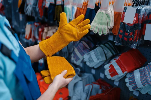 制服を着た男性労働者が工具店に手袋をはめる ハードウェアショップ 楽器スーパーマーケットでのプロの機器の選択 — ストック写真