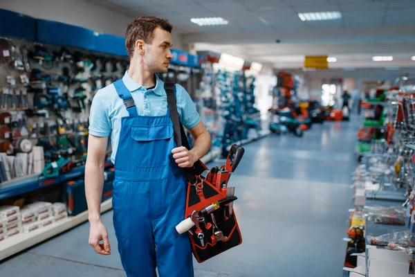 制服を着た男性労働者は工具店に道具箱を持っている ハードウェアショップでのプロの機器の選択 — ストック写真