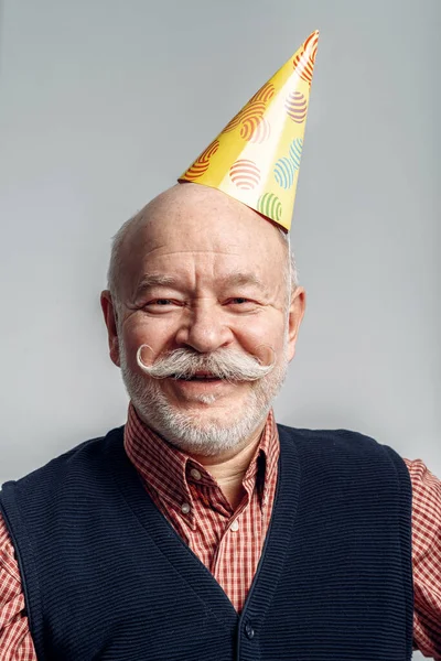 Portret Van Een Glimlachende Oudere Man Met Een Feestmuts Geïsoleerd — Stockfoto