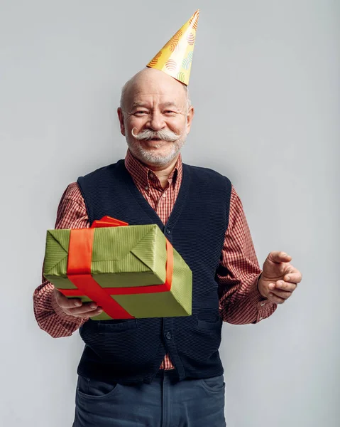 Счастливый Пожилой Человек Кепке Держит Подарочную Коробку Серый Фон Веселый — стоковое фото