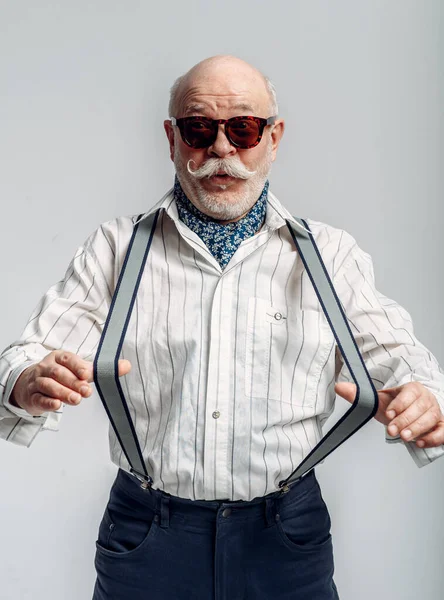 Modieuze Oudere Man Broek Met Bretels Zonnebril Grijze Achtergrond Volwassen — Stockfoto