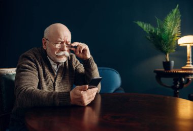 Ofiste cep telefonu kullanan yaşlı bir adam. Sakallı, olgun, akıllı telefonları oturma odasında, yaşlı iş adamı.