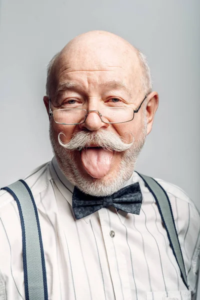 Retrato Homem Idoso Gravata Borboleta Óculos Mostrando Sua Língua Fundo — Fotografia de Stock