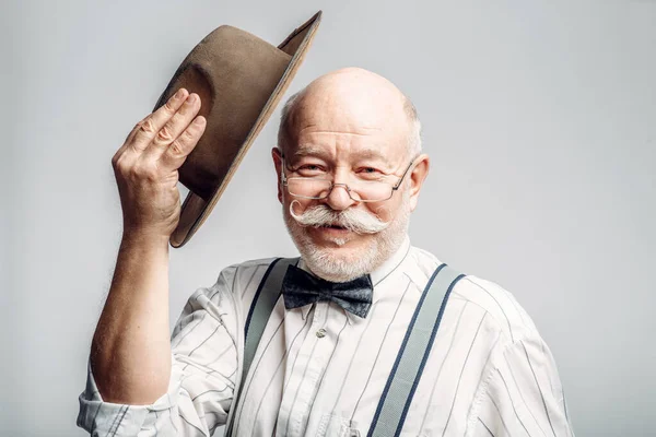 Пожилой Человек Бабочке Очках Снимает Шляпу Серый Фон Зрелый Старший — стоковое фото