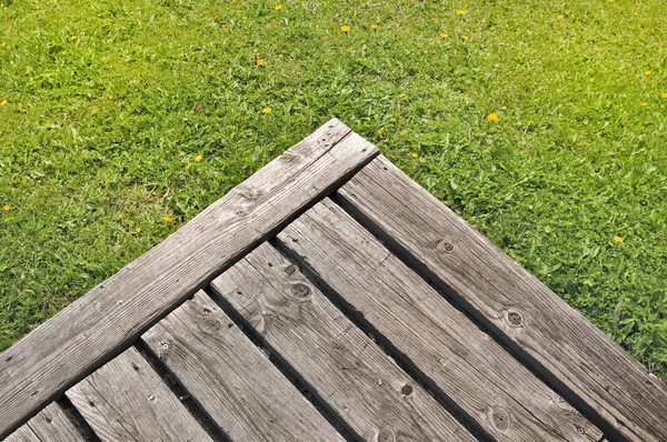 Corner of wooden terrace on green grass — Stock Photo, Image