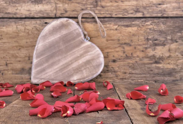 Petals and wooden heart — Stock Photo, Image