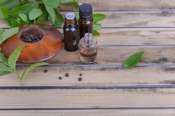 Minyak esensial dari peppermint dalam botol dan daun segar mint dengan lada — Stok Foto