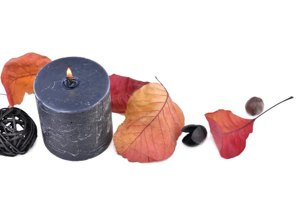 Black candlburning with autumnal leaf on white background — Stock Photo, Image