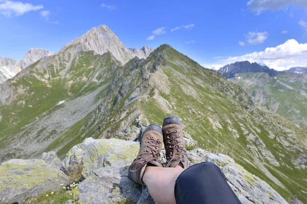 Foot and legs of a hiker sitting at the top of  alpine mountain — Stock Photo, Image