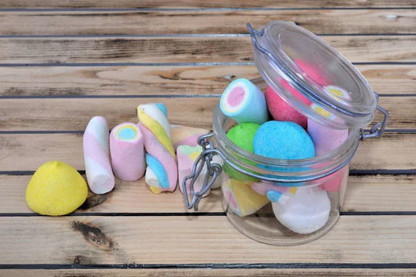 Colorful marshmallows in a glass jar on a wooden background — Stock Photo, Image