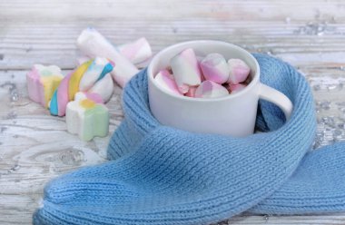 Masadaki mavi çocuk eşarbının üzerindeki şekerlemelerle dolu kupa.