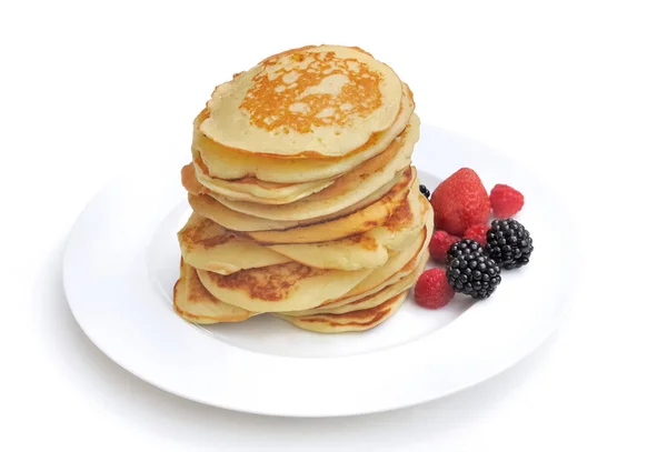 Pile de crêpes fraîches maison sur une assiette avec quelques baies sur fond blanc — Photo