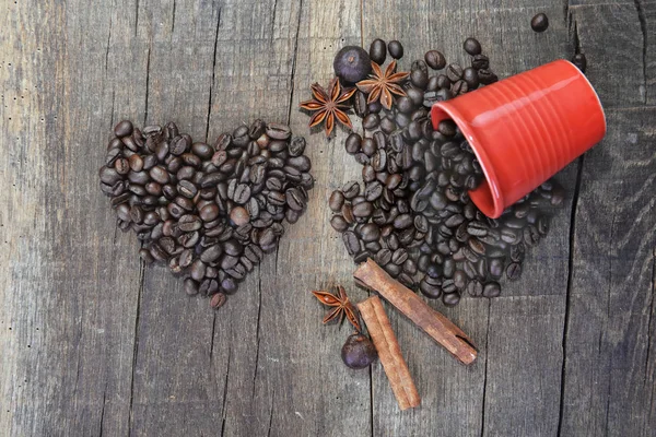 Corazón en forma de granos de café y una taza roja derramada con un concepto de especias de San Valentín — Foto de Stock