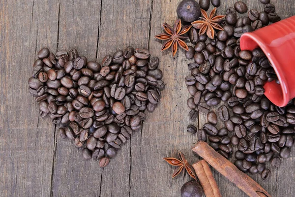 Corazón en forma de granos de café y una taza roja derramada con un concepto de especias de San Valentín — Foto de Stock