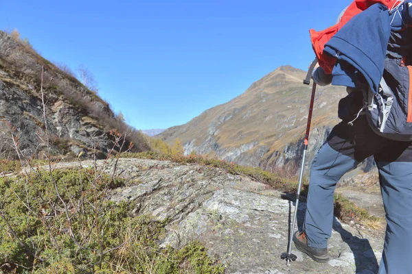 站在高山上蓝天下岩石上的徒步旅行者的腿 — 图库照片