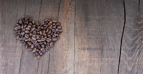 Montón de granos de café formando un corazón en una tabla rústica con sapce copia a la derecha — Foto de Stock