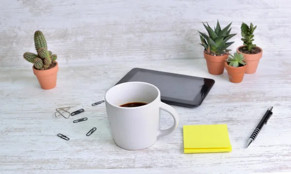 Egy bögre kávé egy íróasztalon tollal és papírcsipesszel és kaktusz cserepes — Stock Fotó