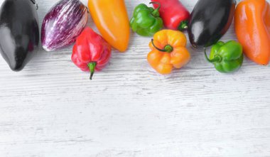 Beyaz bir masaya dizilmiş renkli biber ve patlıcan koleksiyonu. 