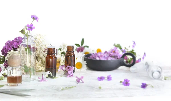 白いテーブルの上にエッセンシャルオイルと鮮やかな花のカラフルな花びらのボトル — ストック写真