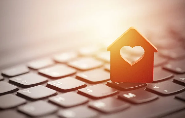 Small red house with heart over laptop keyboard — Stock Photo, Image